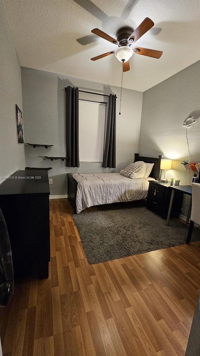 bedroom with ceiling fan, a textured ceiling, and dark hardwood / wood-style flooring