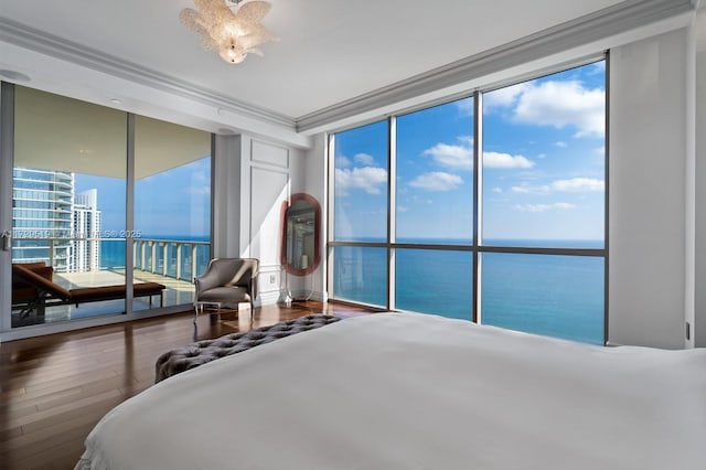 bedroom featuring expansive windows, ornamental molding, a water view, and hardwood / wood-style flooring