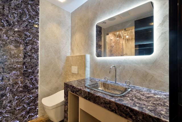 bathroom with vanity, tile walls, and toilet