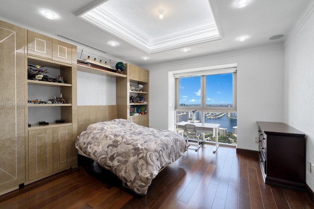 bedroom with dark wood-type flooring, ornamental molding, a raised ceiling, and a water view