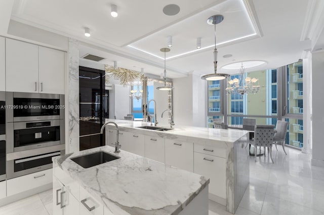 kitchen with pendant lighting, white cabinets, sink, and a spacious island