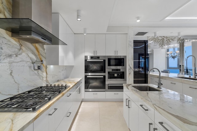 kitchen with white cabinets, appliances with stainless steel finishes, sink, and wall chimney range hood