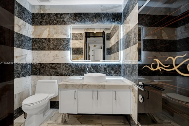 bathroom with vanity, tile walls, and toilet