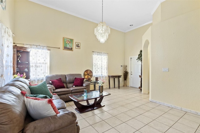 tiled living room with ornamental molding, a towering ceiling, and an inviting chandelier