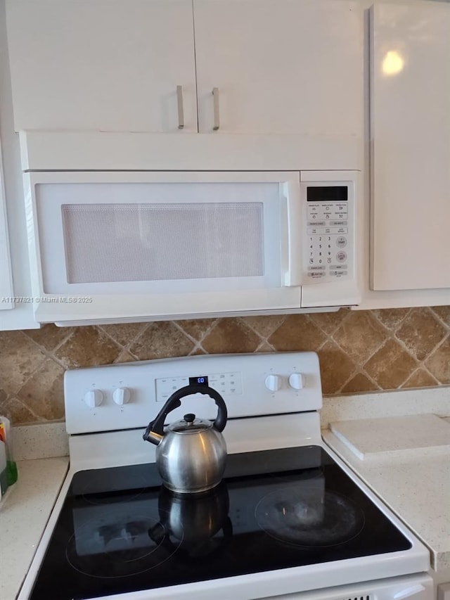 details with tasteful backsplash, white cabinetry, and white appliances