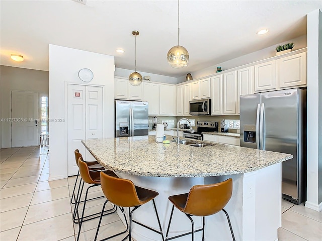 kitchen with white cabinetry, appliances with stainless steel finishes, a center island with sink, and light tile patterned floors