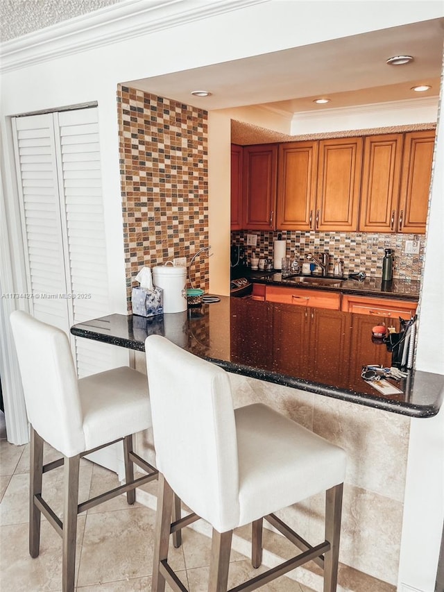 kitchen with ornamental molding, sink, tasteful backsplash, and dark stone countertops