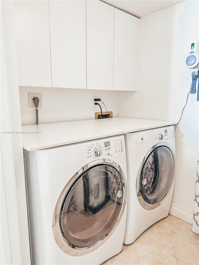 washroom featuring cabinets, washing machine and dryer, and light tile patterned floors