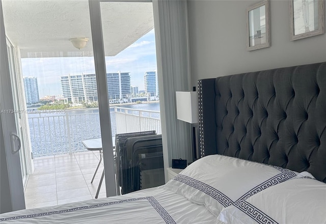 tiled bedroom featuring a textured ceiling and a water view