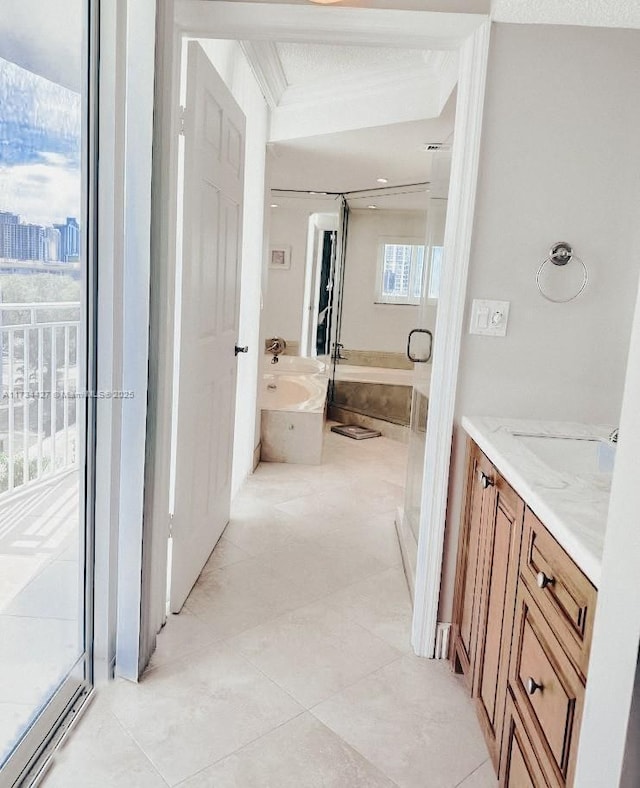 bathroom with tile patterned floors, crown molding, vanity, and a relaxing tiled tub