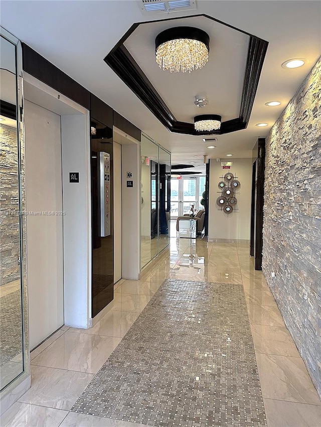 hall featuring a tray ceiling and elevator