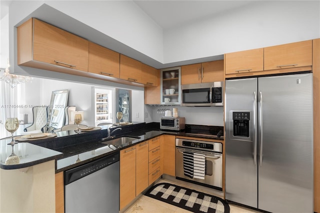 kitchen featuring light tile patterned flooring, sink, appliances with stainless steel finishes, kitchen peninsula, and dark stone counters