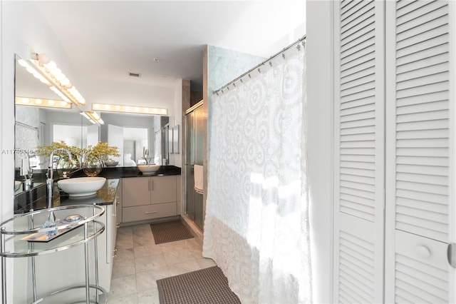 bathroom with tiled shower, vanity, and tile patterned flooring