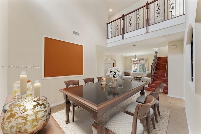 tiled dining room featuring a towering ceiling and a notable chandelier