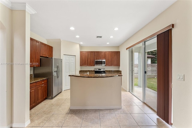 kitchen with appliances with stainless steel finishes, a center island, dark stone countertops, and light tile patterned floors