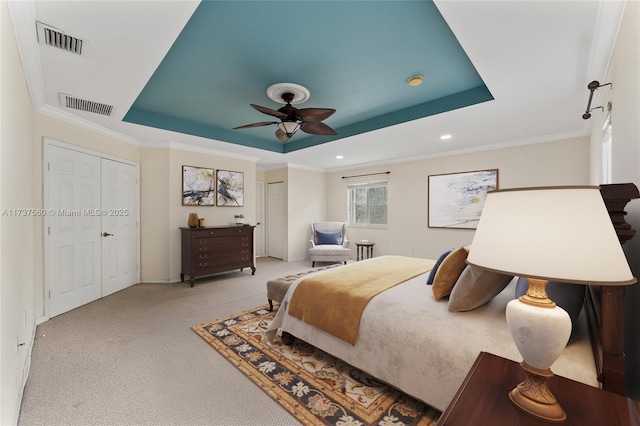 carpeted bedroom featuring a tray ceiling, ornamental molding, and ceiling fan