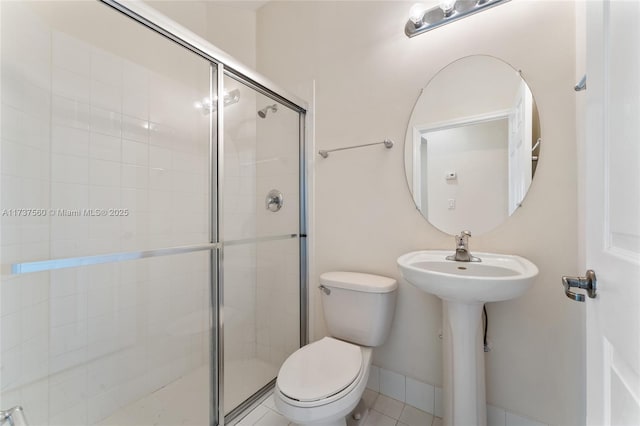 bathroom with sink, toilet, an enclosed shower, and tile patterned flooring