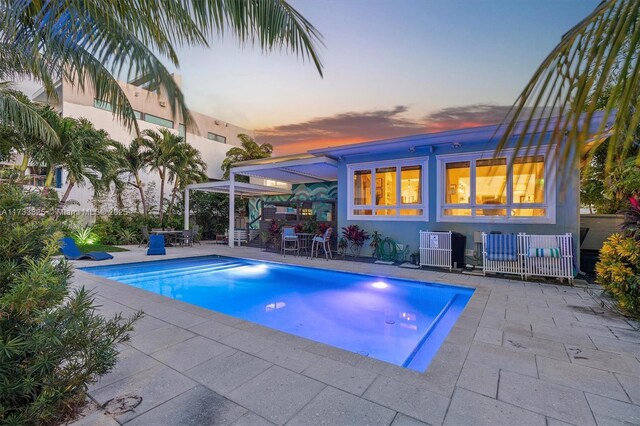 pool at dusk with a patio area