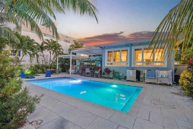 pool at dusk with a patio area