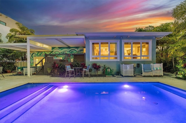 pool at dusk featuring a patio