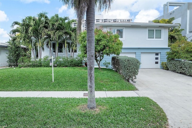 view of front facade with an attached garage, a front lawn, concrete driveway, and stucco siding