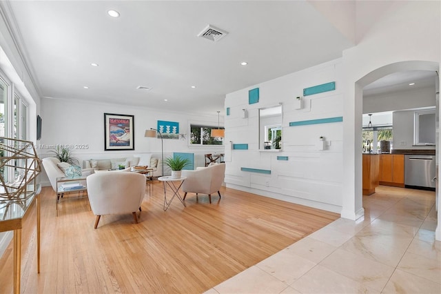 living room with arched walkways, recessed lighting, visible vents, light wood-style floors, and ornamental molding