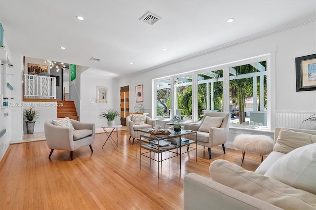 living area with light wood-style floors, stairs, visible vents, and crown molding