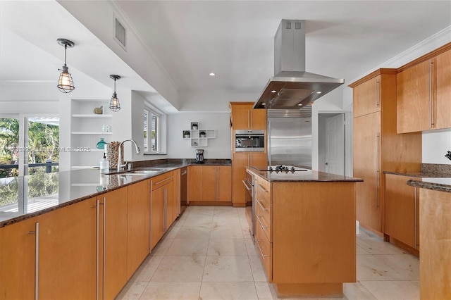 kitchen featuring appliances with stainless steel finishes, dark stone countertops, a peninsula, island exhaust hood, and a sink