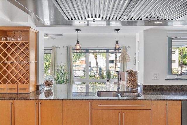 kitchen featuring dark stone counters, a sink, and pendant lighting