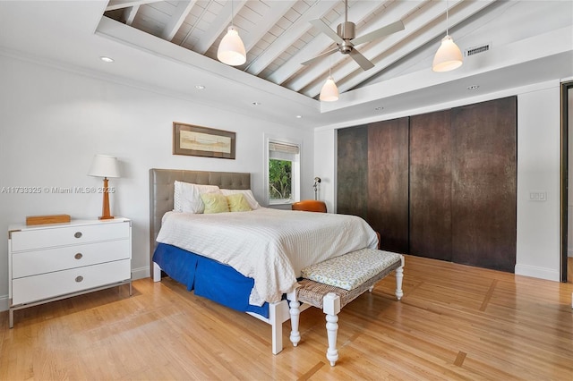 bedroom featuring lofted ceiling with beams, light wood finished floors, baseboards, and visible vents