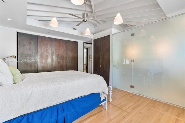 bedroom with visible vents, a ceiling fan, wood finished floors, vaulted ceiling with beams, and multiple closets