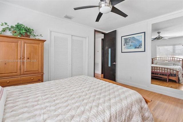 bedroom featuring light wood-style flooring, visible vents, baseboards, ornamental molding, and a closet