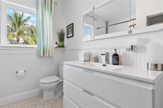 bathroom with a wainscoted wall, vanity, and toilet