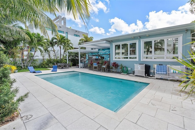 pool with a patio area, fence, and cooling unit