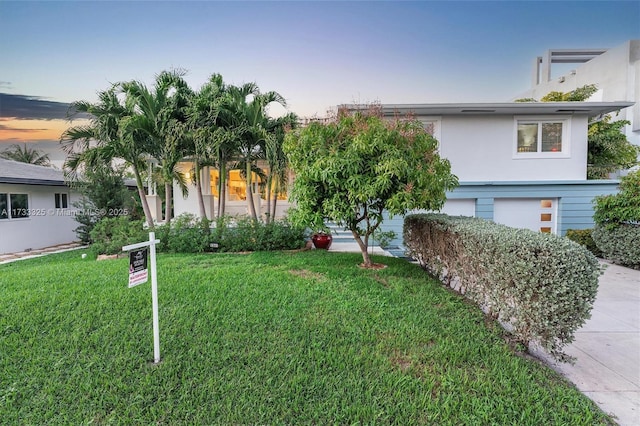 view of front of home with an attached garage, a front lawn, and stucco siding