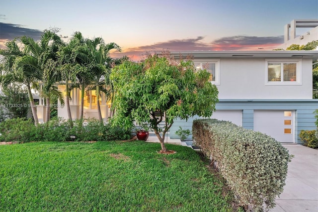 view of front of house featuring a front yard, driveway, an attached garage, and stucco siding