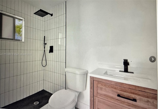 bathroom featuring vanity, tiled shower, and toilet