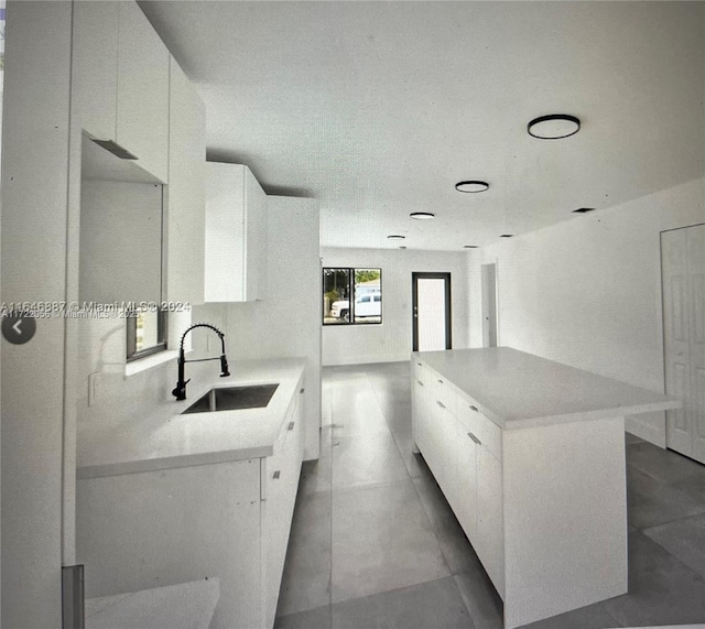 kitchen with a kitchen island, sink, and white cabinetry