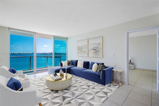 tiled living room featuring a water view, floor to ceiling windows, and a textured ceiling