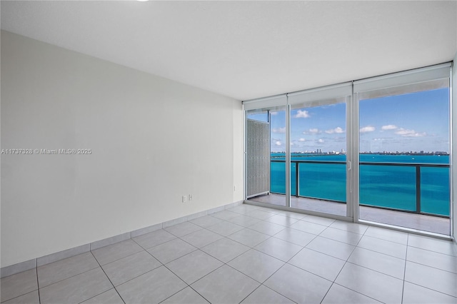 tiled spare room featuring a water view and floor to ceiling windows