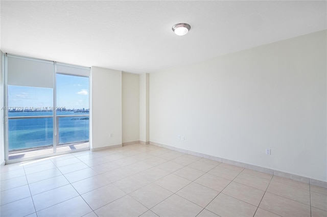 tiled spare room with a water view and expansive windows