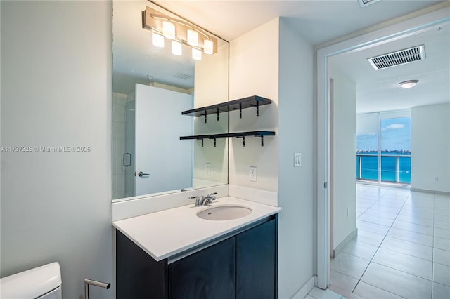 bathroom with tile patterned flooring, vanity, toilet, and walk in shower