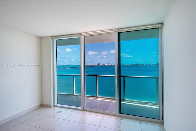 spare room featuring a water view, light tile patterned floors, and expansive windows