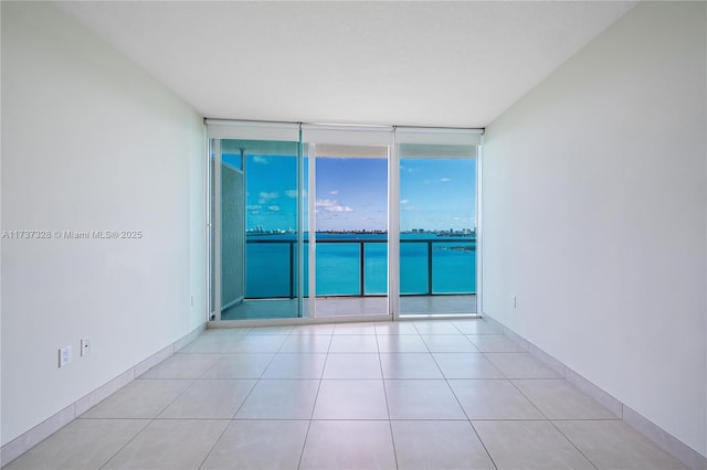 empty room featuring a wall of windows and light tile patterned floors