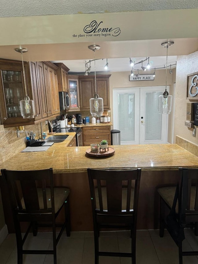 kitchen with hanging light fixtures, stainless steel appliances, kitchen peninsula, and a kitchen bar