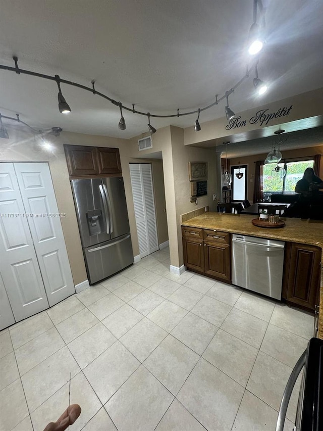 kitchen with dark brown cabinetry, appliances with stainless steel finishes, and light tile patterned floors