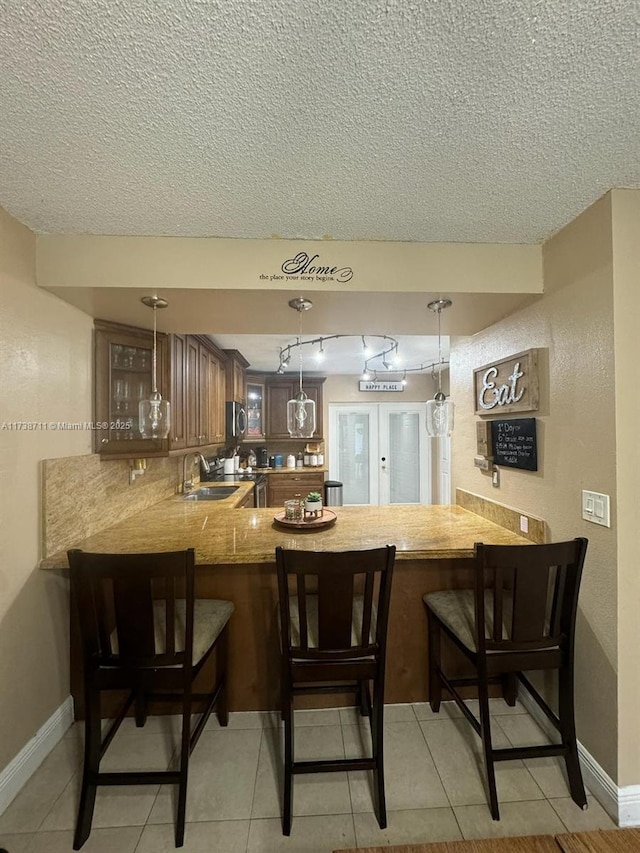 kitchen featuring pendant lighting, kitchen peninsula, sink, and a breakfast bar area