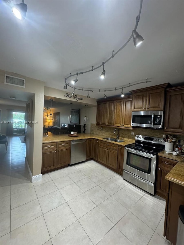 kitchen featuring sink, light tile patterned floors, appliances with stainless steel finishes, hanging light fixtures, and decorative backsplash