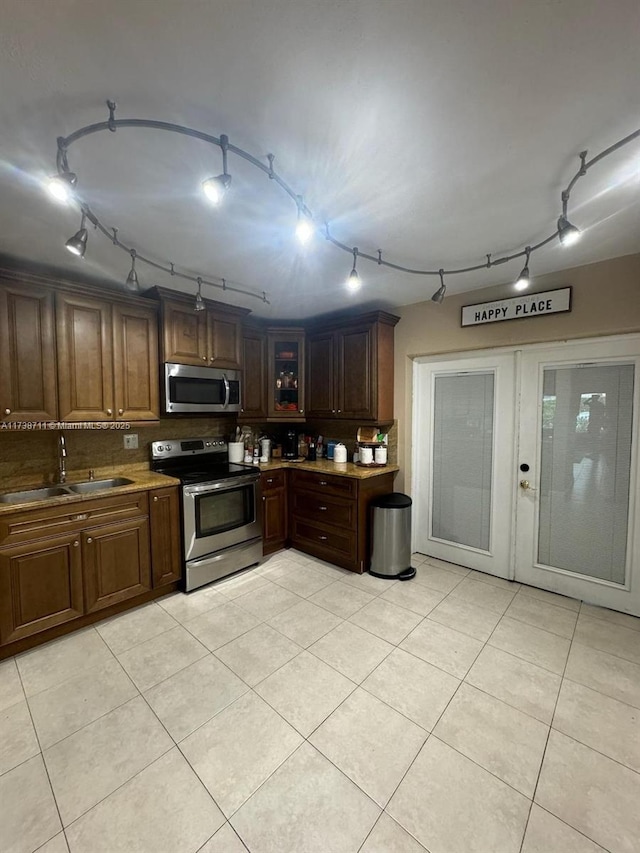 kitchen with rail lighting, sink, light tile patterned floors, appliances with stainless steel finishes, and backsplash