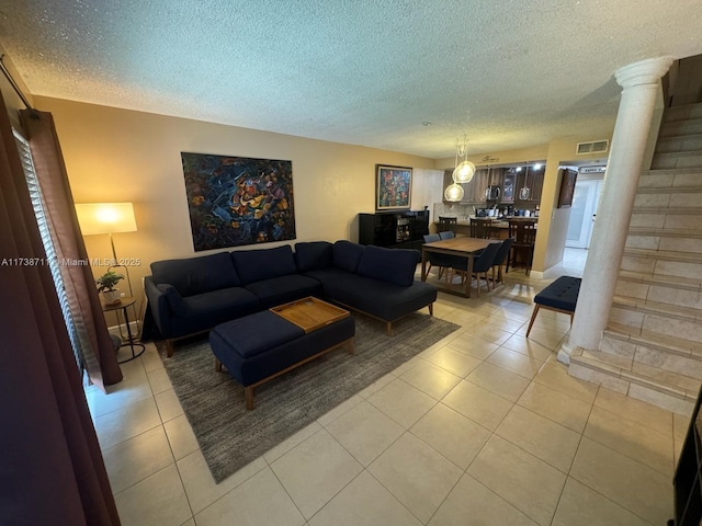 tiled living room featuring decorative columns and a textured ceiling